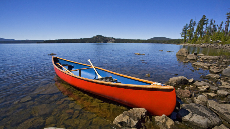 Un canoë rouge se trouve sur les rives rocheuses du lac Waldo