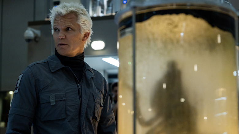 Kirsh se tient devant un réservoir contenant une créature extraterrestre en extraterrestre: la Terre