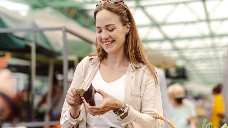Femme qui tire de l'argent sur un marché