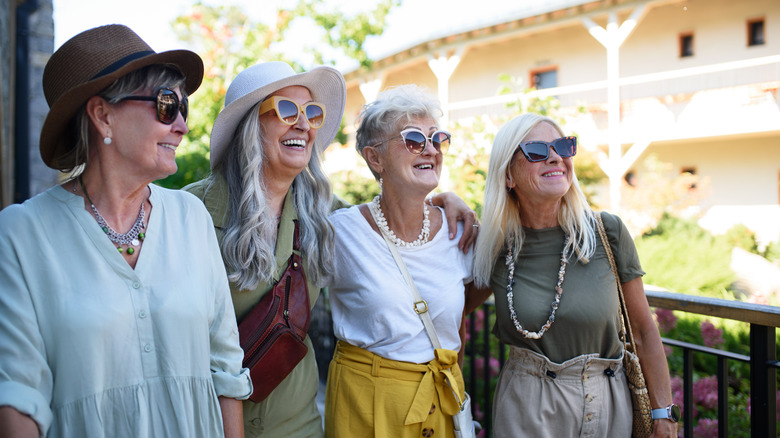 Quatre femmes âgées sourient et posent ensemble dans un endroit ensoleillé