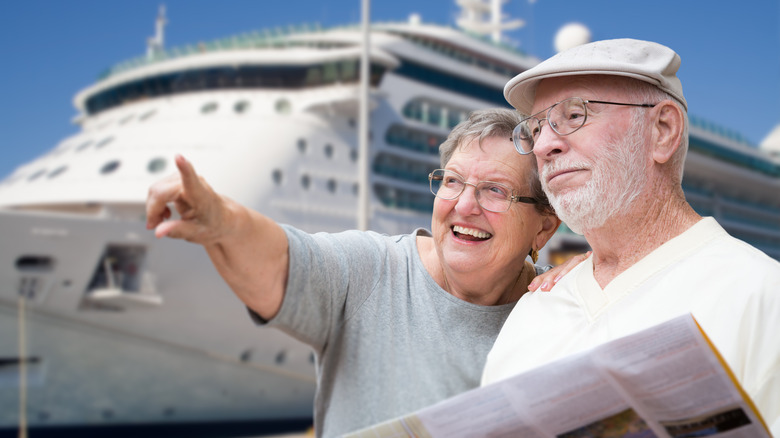 Un couple senior regarde le loin devant un bateau de croisière