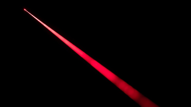 Un faisceau laser rouge est vu sur un fond noir