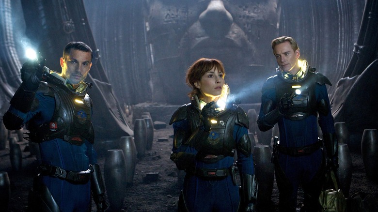 Logan Marshall-Green en tant que Charlie Holloway, Noomi Rapace comme Elizabeth Shaw et Michael Fassbender comme David explorant une pièce inconnue remplie de conteneurs ovales à Prometheus