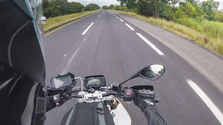 Un motard portant un casque utilisant la navigation GPS mobile sur son téléphone intelligent