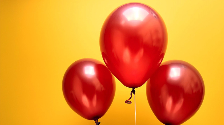 Trois ballons rouges brillants situés sur un fond jaune vibrant