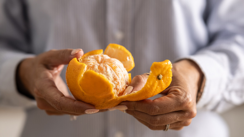 Les mains d'un homme tiennent une orange semi-pelu