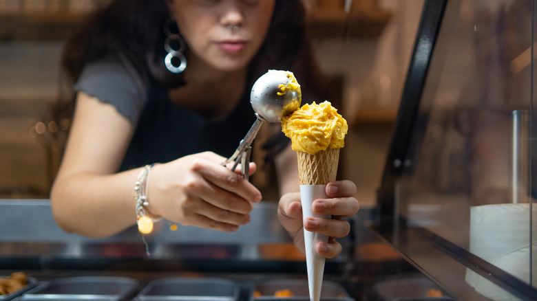 Un travailleur ramassant du gelato dans un cône.