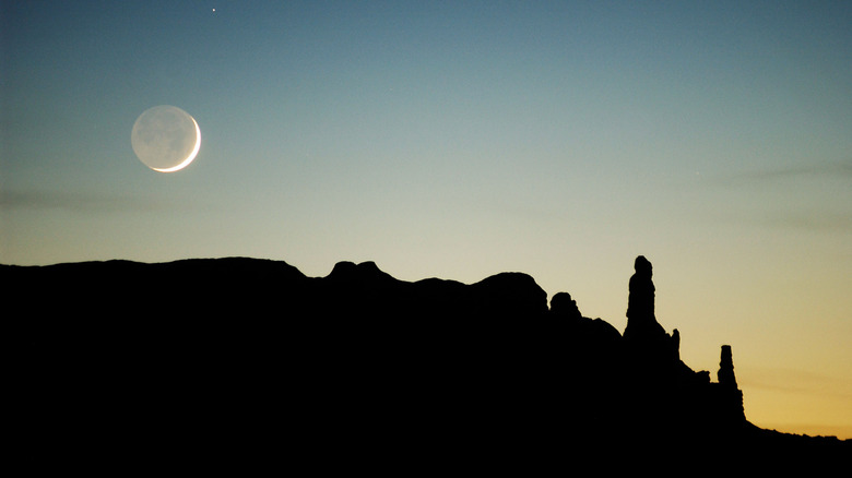 Lune sur la silhouette des rochers du désert au crépuscule