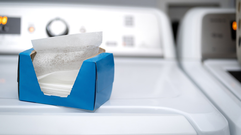 Une boîte de feuilles de séchage assise sur une machine à laver.