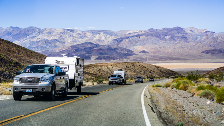 Une rangée de camions et de voitures avec des remorques roulant le long de l'autoroute à Death Valley
