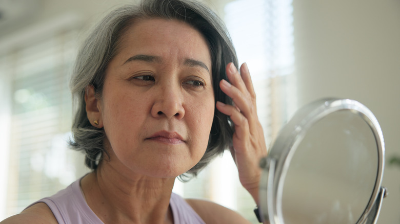 Une femme admirant son travail de Botox autour de ses pieds de cordes dans le miroir