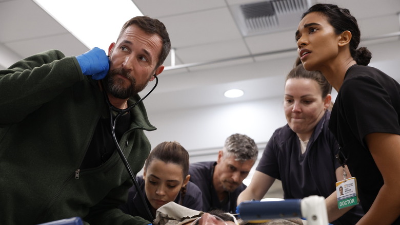 Robby et Mohan avec des médecins et des infirmières supervisant un patient traumatisé sur le Pitt