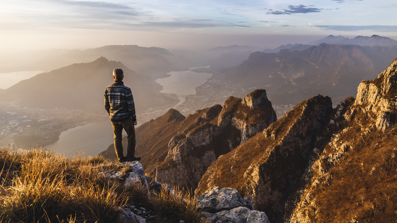 Un randonneur regarde du sommet d'une montagne au lac Croom, en Italie