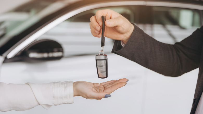 Une main laisse tomber une clé de voiture dans une autre main