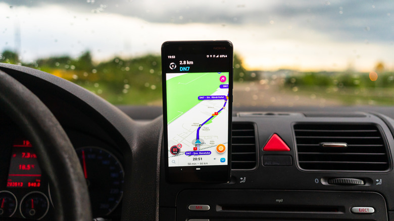 Écran de navigation de l'application Waze sur un téléphone mobile sur le tableau de bord d'une voiture.