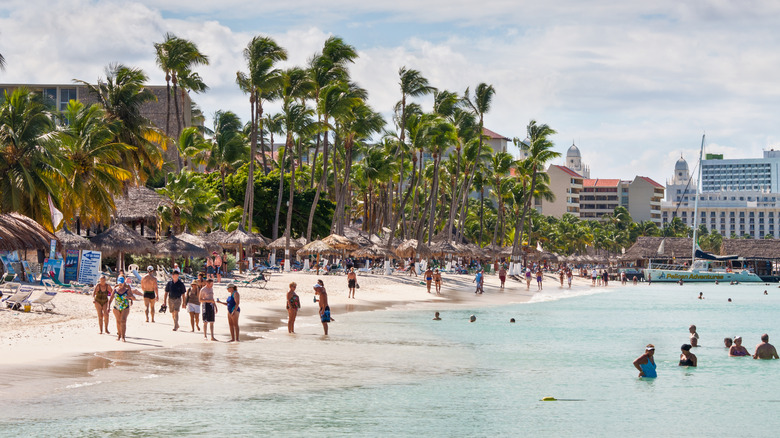 une plage bondée avec des palmiers et de grands bâtiments
