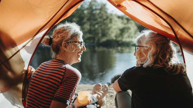 Deux femmes se souriant dans une tente par rivière
