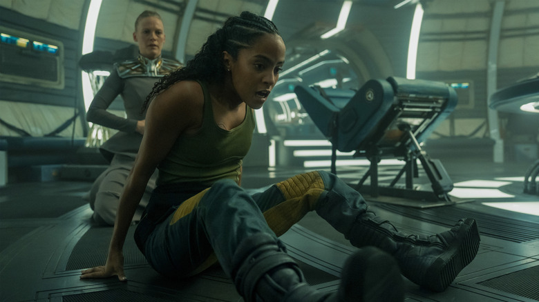 Lou Llobell en tant que Gaal Dornick assis au sol comme Laura Birn alors que Demerzel s'agenouille derrière elle dans la fondation