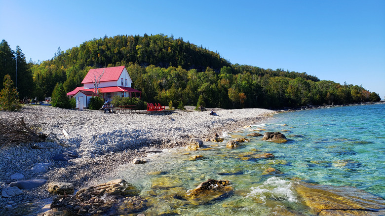 Une plage rocheuse avec des eaux turquoise et un bâtiment à toit rouge