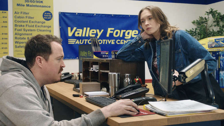 Veronika Slowikowska alors que Kelly regarde Shane Gillis comme Shane derrière le bureau des pneus de Netflix