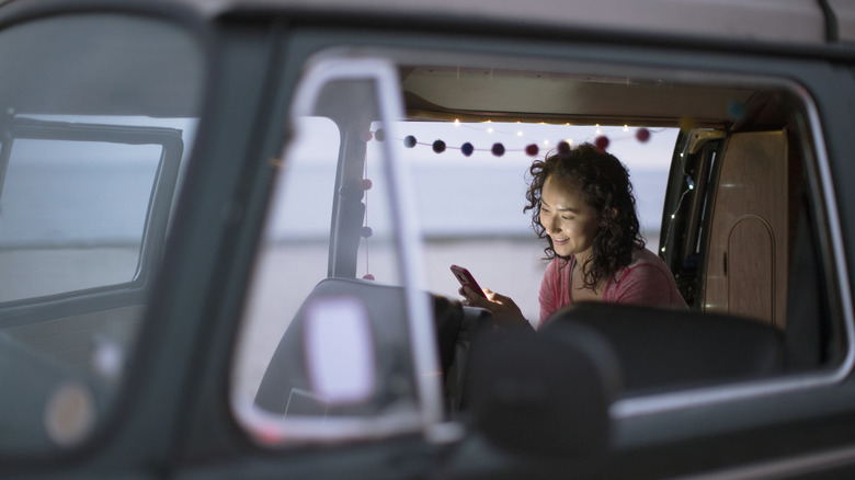 Femme dans un camping-car regardant le téléphone mobile