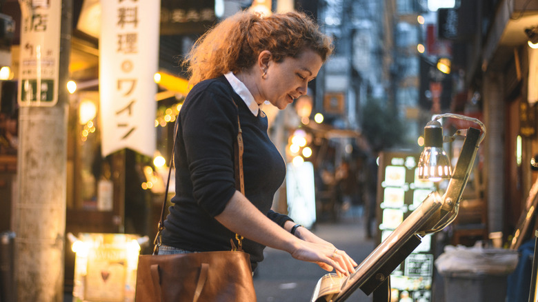 Femme qui regarde un menu à l'extérieur d'un restaurant