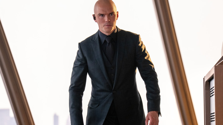 Nicholas Hoult comme Lex Luthor portant un costume et un écouteur avec une expression sérieuse sur son visage à Superman