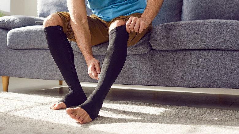 Une personne qui met des chaussettes de compression noires.