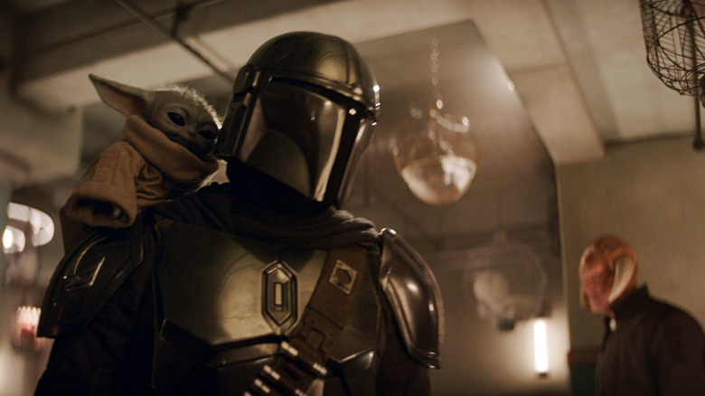 Grogu perche sur l'épaule de Din Djarin dans le mandalorien et Grogu.