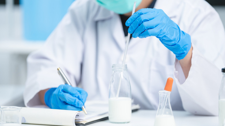 Food Scientist écrit des notes tout en observant un verre de lait