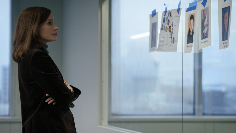 Jessica Chastain comme Jodi Goodwin se tenant dans un bureau et regardant des images collées sur une fenêtre dans le Savant