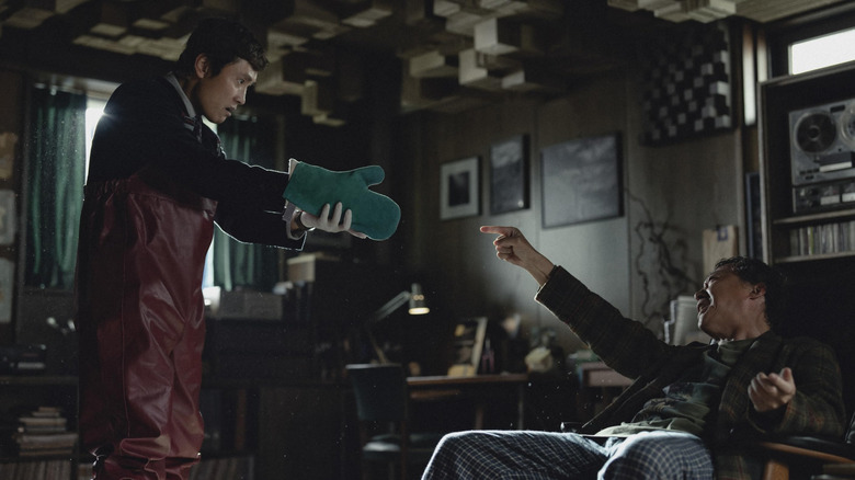 Lee Byung-Hun en tant qu'homme-soo tenant ce qui semble être une arme pour un homme assis sur une chaise sans autre choix