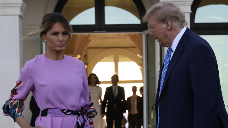 Melania Trump dans une robe violette debout avec Donald Trump dans un costume bleu