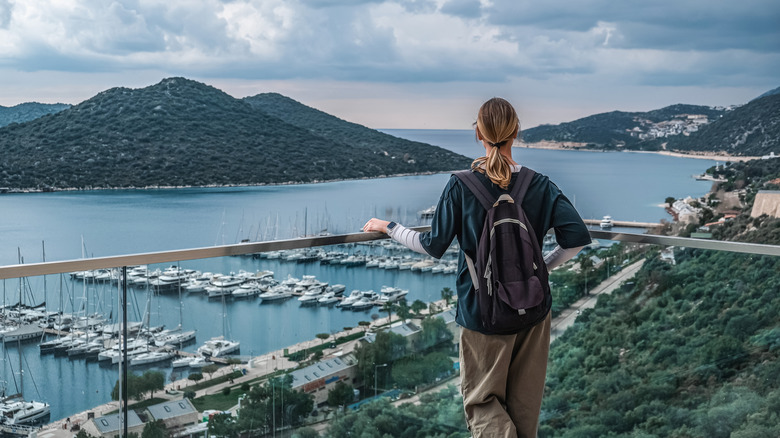 Voyage en solo avec sac à dos profitant de la vue d'une île avec des bateaux