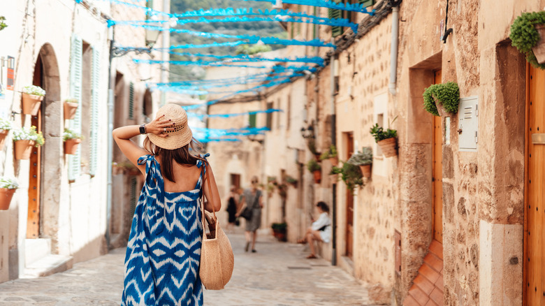 Un arrière-plan d'une femme portant une robe bleue et un chapeau marchant dans les rues pavées