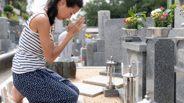 Une femme prie devant un site grave au Japon