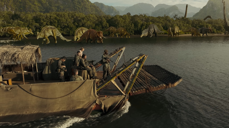 L'équipe sur le bateau regardant divers dinosaures sur le rivage en guerre primitive