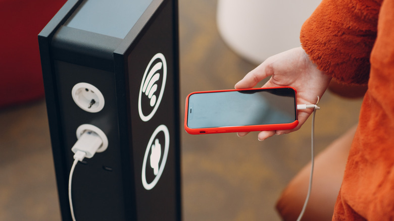 Personne facturant un iPhone sur un quai de chargement public