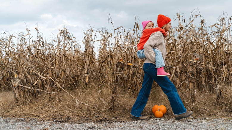 Une mère portant sa jeune fille par des tiges de maïs d'automne