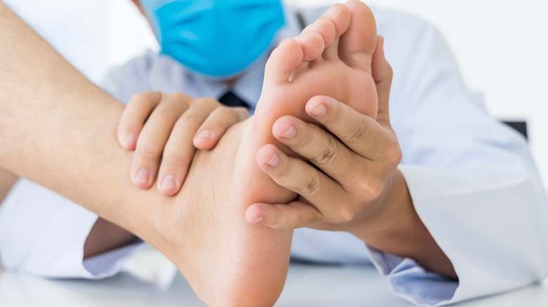 Docteur tenant la semelle du pied d'un patient