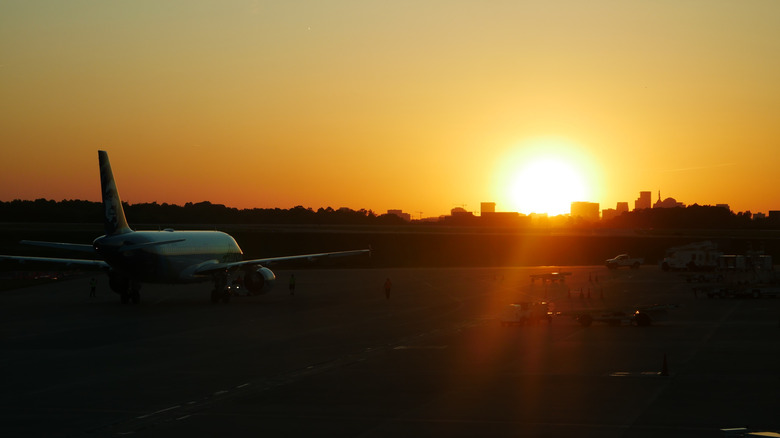 Un avion sur une piste au coucher du soleil