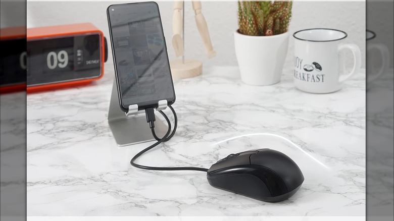 Une souris connectée à un smartphone Android sur une table en marbre.