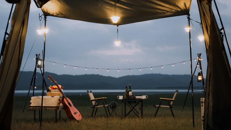 Une configuration de camping romantique avec une guitare et des guirlandes lumineuses au bord d'un lac.
