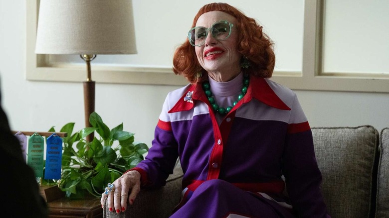 Gladys souriant avec des lunettes vertes dans le bureau de Marcus sur les armes