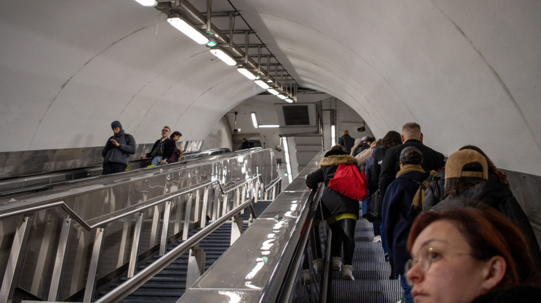 Des gens qui montent sur un escalator dans un tunnel.