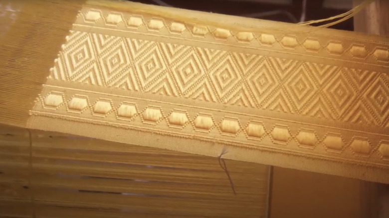 Une cape en soie d'araignée tisserande dorée est vue en gros plan