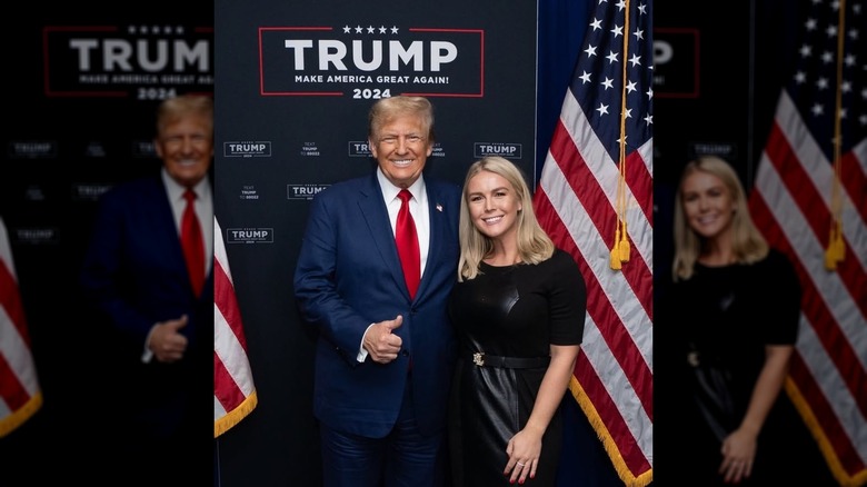 Une photo de Karoline Leavitt debout avec Donald Trump devant deux drapeaux américains et un Trump 