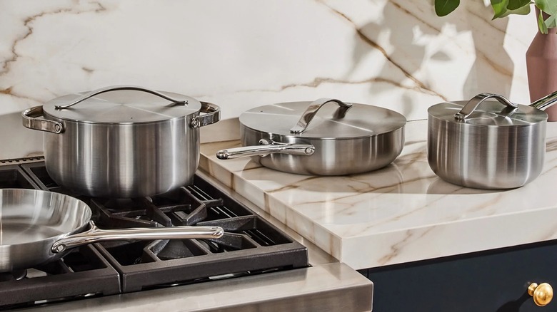 Batterie de cuisine en acier inoxydable au carvi sur cuisinière à gaz et comptoir en faux marbre