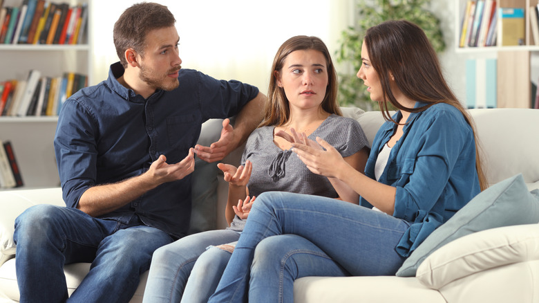 Une famille multigénérationnelle assise autour d’une table et trinquant avec des verres de vin rouge