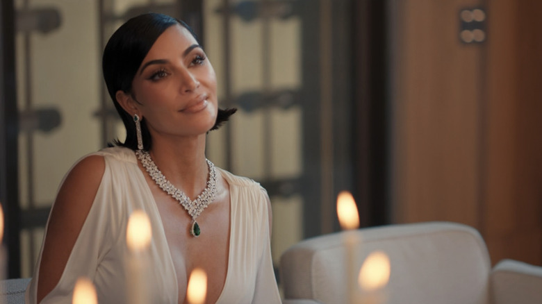 Allura de Kim Kardashian sourit alors qu'elle est assise à une table dans All's Fair
